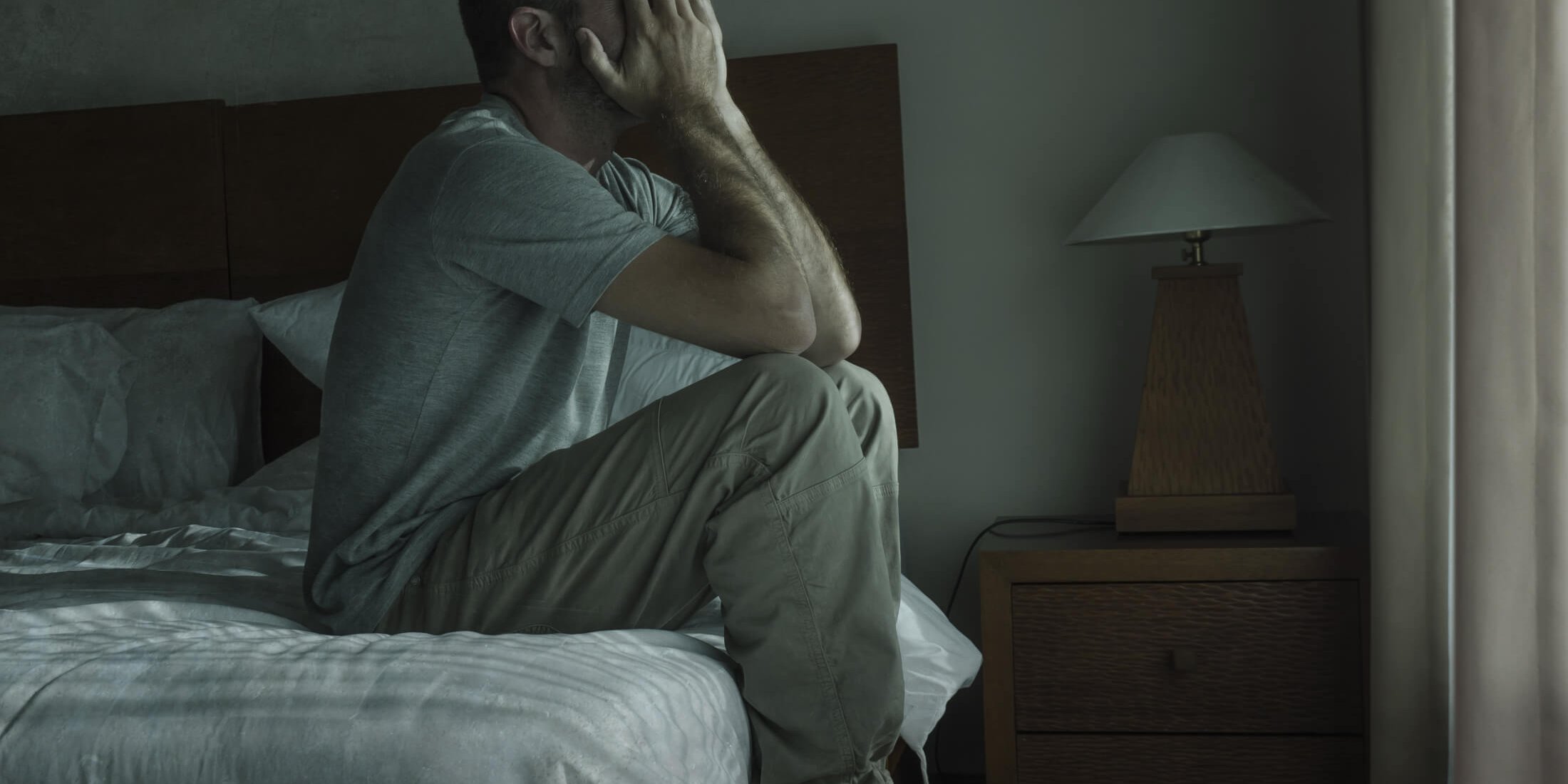 Attractive depressed and sad man at home sitting on bed crying desperate suffering depression problem