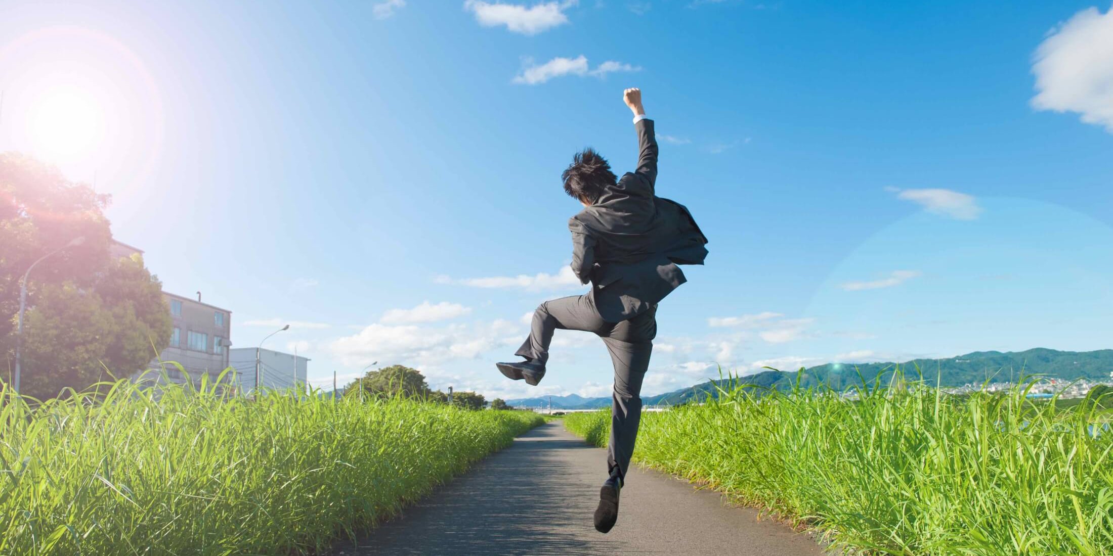 道路でジャンプをするスーツのビジネスマン